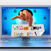 Ransomware attack visualization showing extortion message on laptop with encrypted padlock symbols representing cyber threat